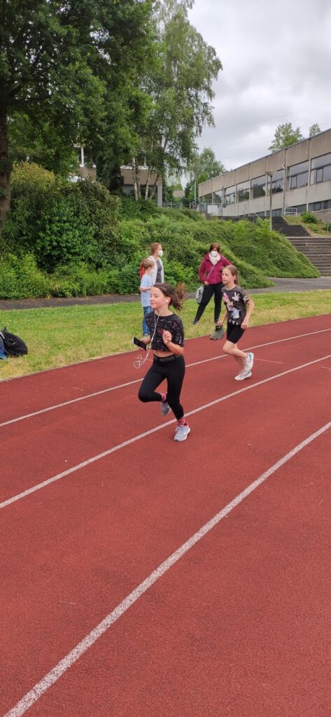 Kinder laufen auf einer Laufbahn während eines Sportevents.