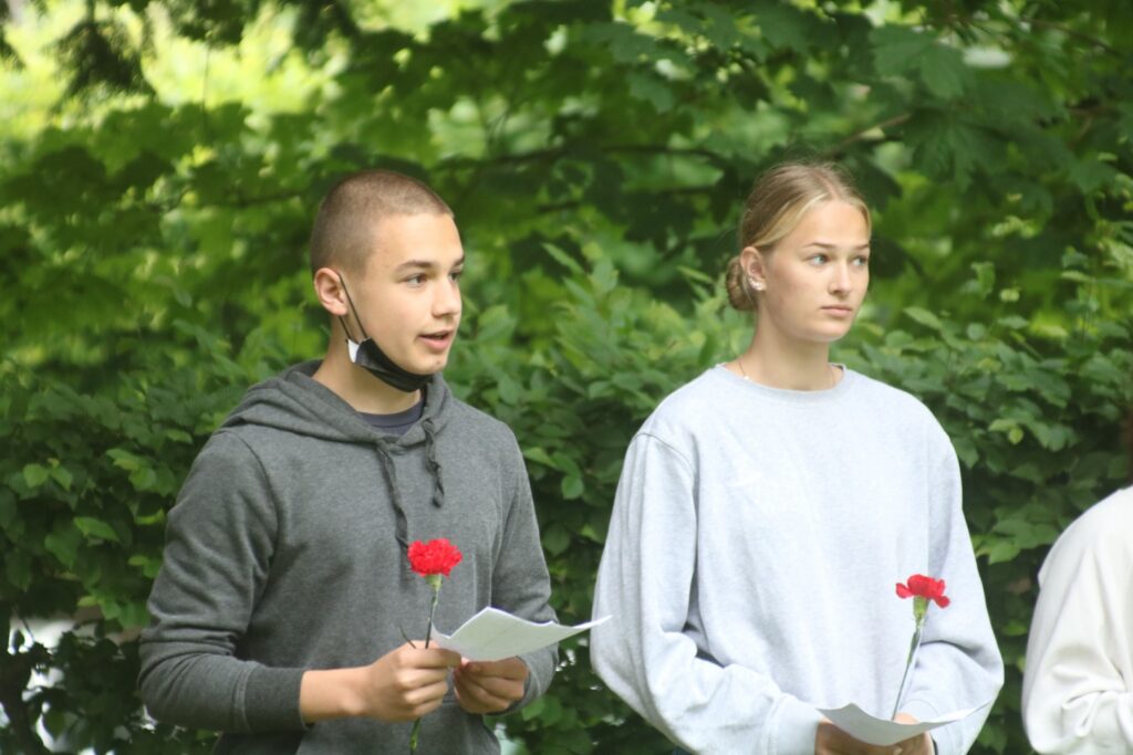Zwei Schülerinnen halten Blumen und stehen im Freien.
