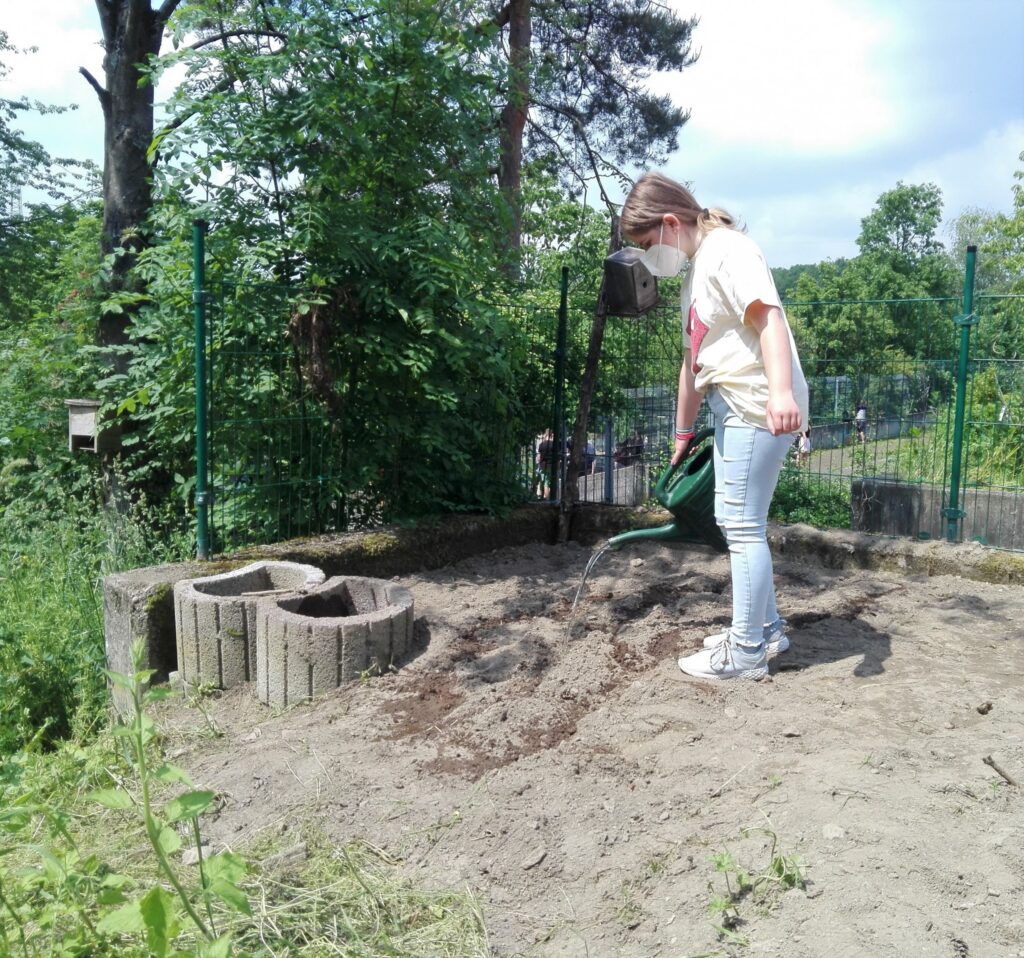 Schülerin arbeitet im Schulgarten und bearbeitet den Boden.