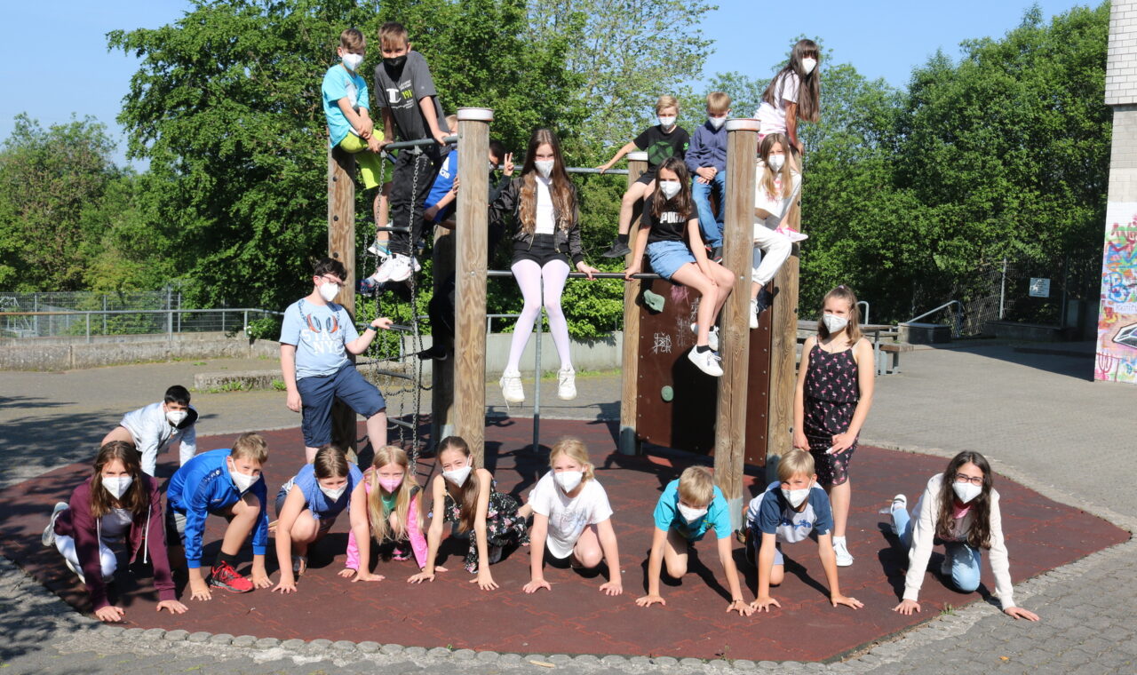 Schülerinnen und Schüler posieren auf einem Spielplatz mit Klettergerüst.