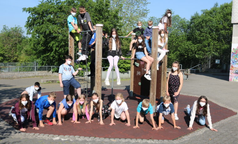 Schülerinnen und Schüler posieren auf einem Spielplatz mit Klettergerüst.