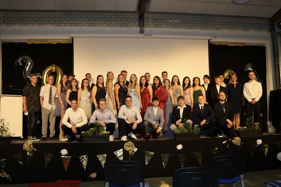 Gruppenfoto von Schülern in festlicher Kleidung auf einer Bühne.