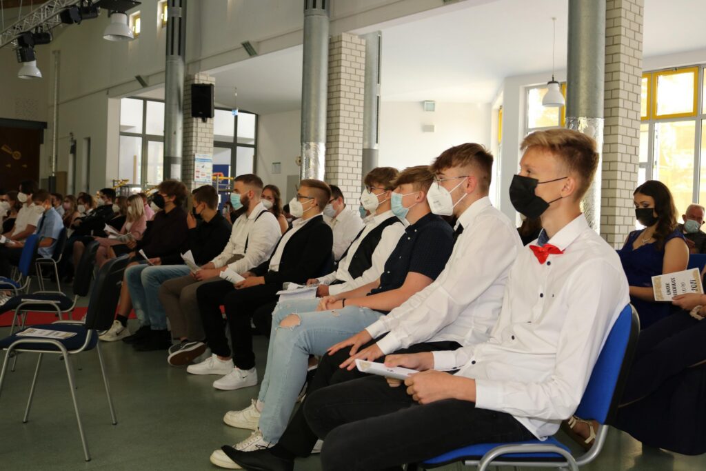 Schüler sitzen in Reihen und hören bei einer Veranstaltung zu.