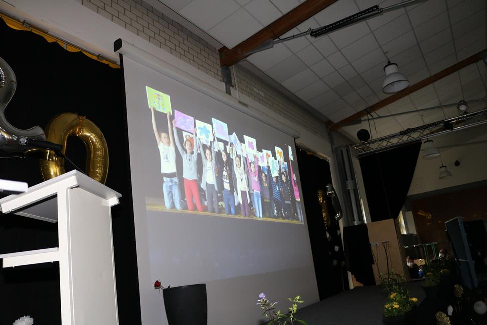 Gruppe von Schülern hält Plakate auf einer Bühne in einer Schulveranstaltung.