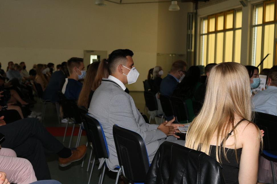 Teilnehmer in einem Saal während einer Veranstaltung, einige tragen Masken.