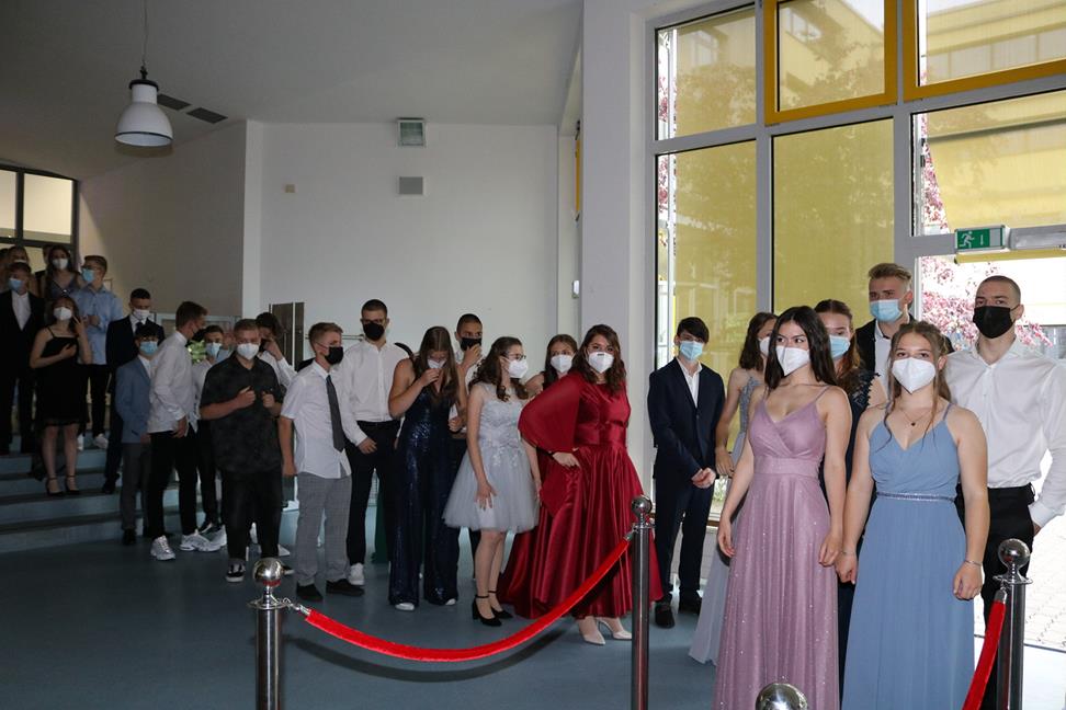 Schülerinnen und Schüler in eleganter Kleidung stehen in einer Schlange.