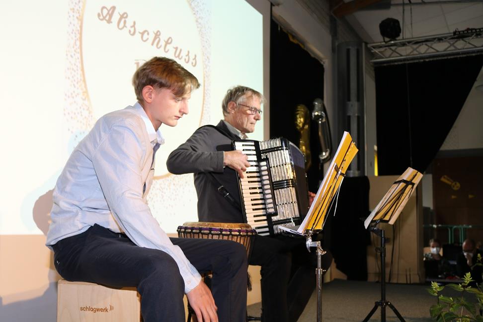 Zwei Musiker auf einer Bühne während einer Abschlussfeier.