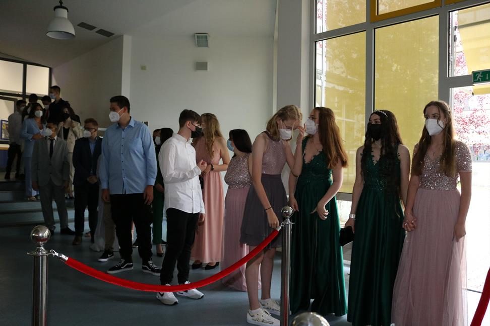 Schülerinnen und Schüler in festlicher Kleidung stehen in einer Schlange.
