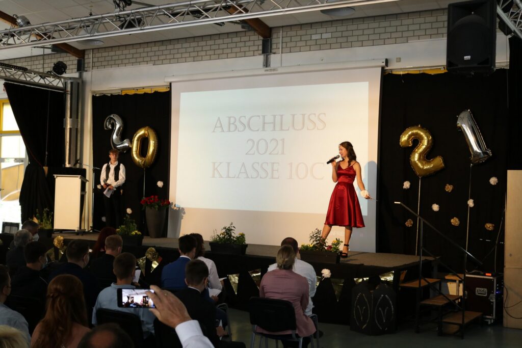 Abschlussfeier 2021 mit Rednern auf der Bühne und Publikum im Vordergrund.