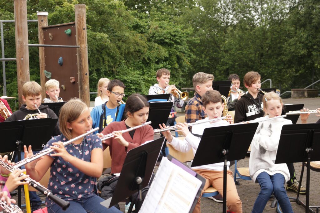 Schüler spielen im Freien in einem Orchester verschiedene Blasinstrumente.
