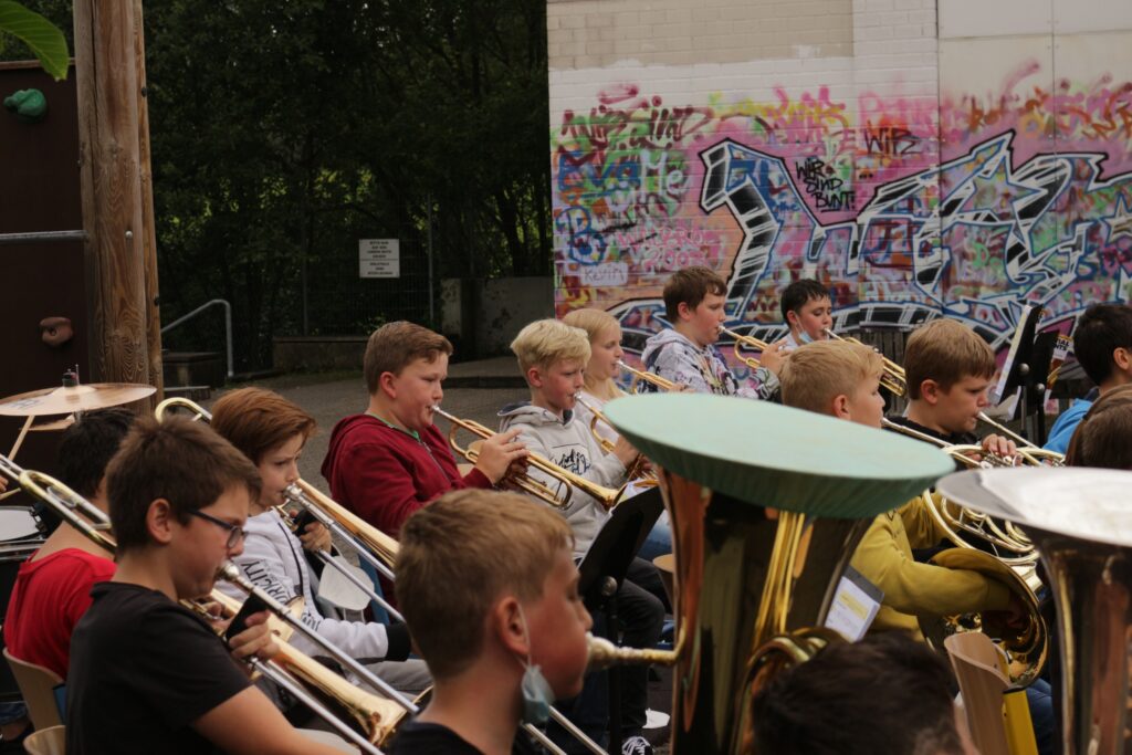 Musikgruppe spielt vor einer bunten Graffiti-Wand.