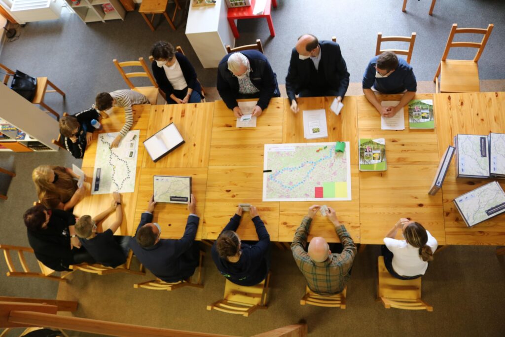 Gruppensitzung an einem großen Tisch mit Karten und Notizen.