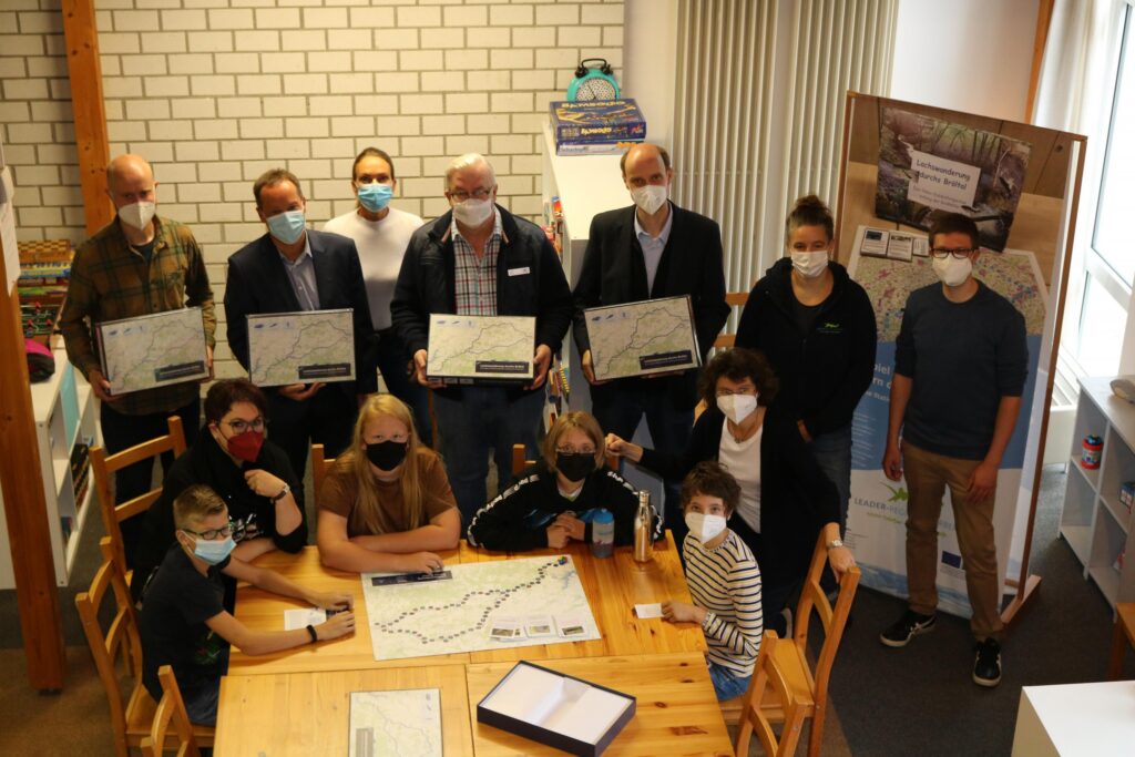 Gruppe von Personen in einem Raum, alle tragen Masken und halten Plakate.