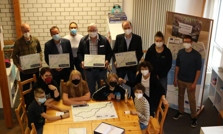 Gruppe von Personen in einem Raum, alle tragen Masken und halten Plakate.