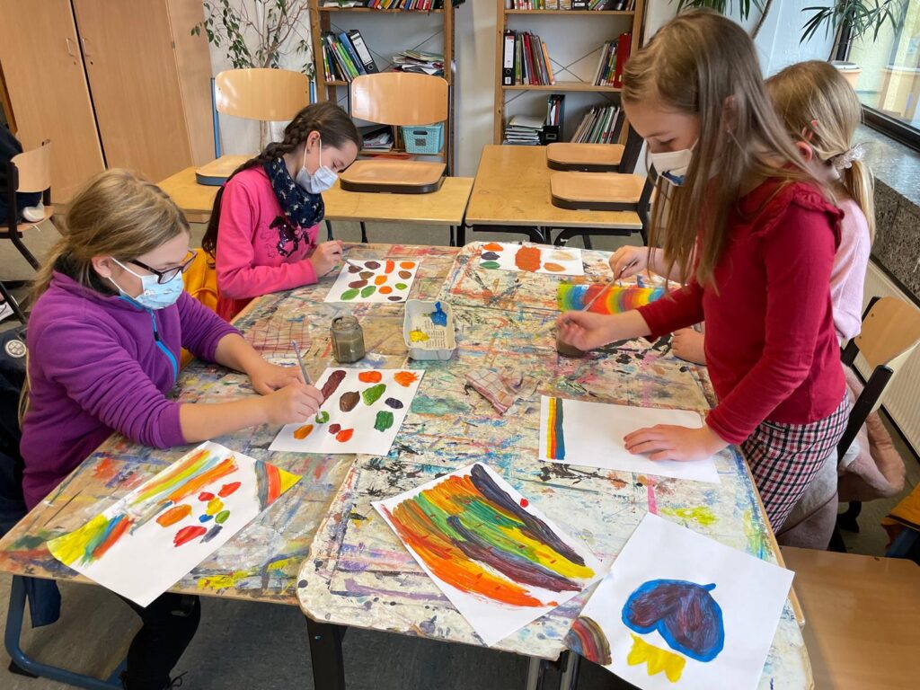 Schülerinnen arbeiten an Kunstprojekten an einem Tisch.