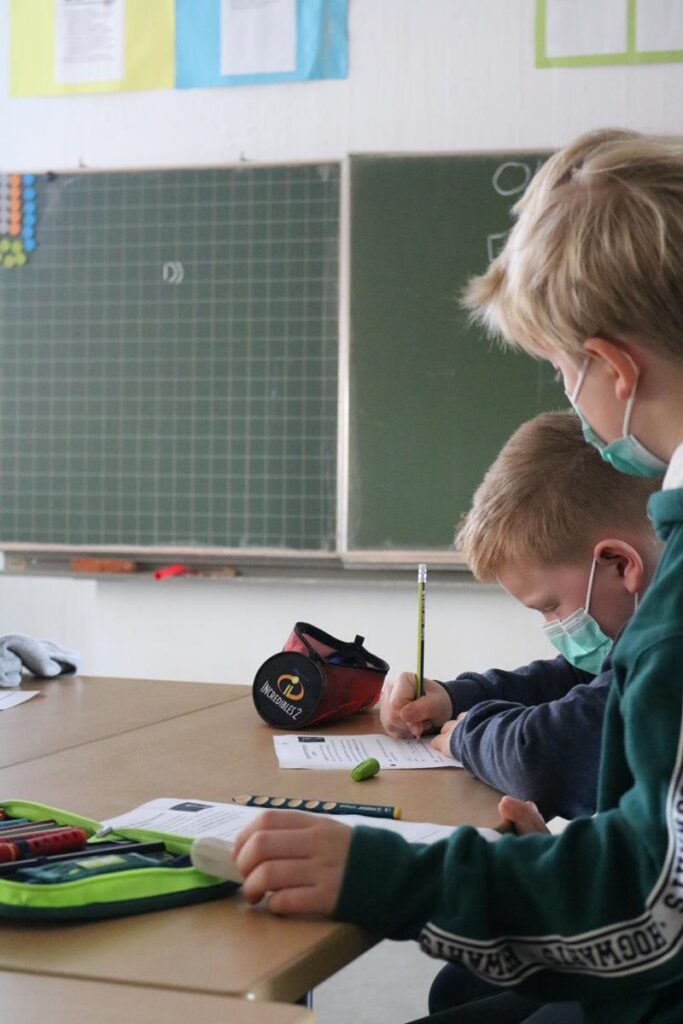 Zwei Schüler sitzen an einem Tisch und arbeiten an Aufgaben.