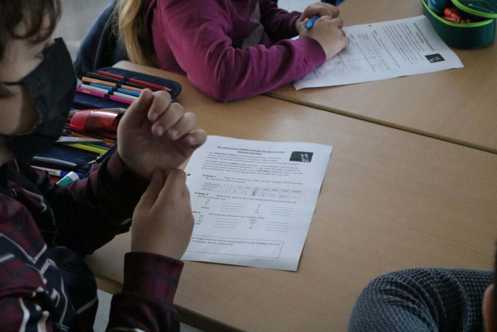 Schüler arbeiten an Aufgaben auf einem Tisch.