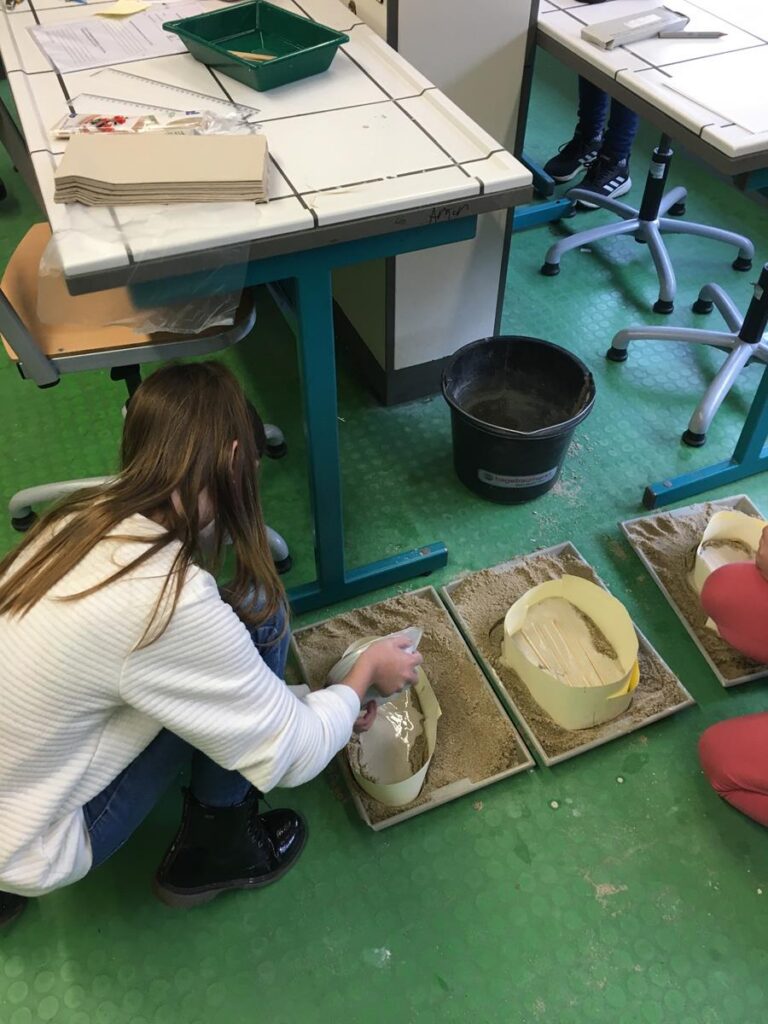 Schülerin arbeitet im Werkraum mit Sand und Formen.