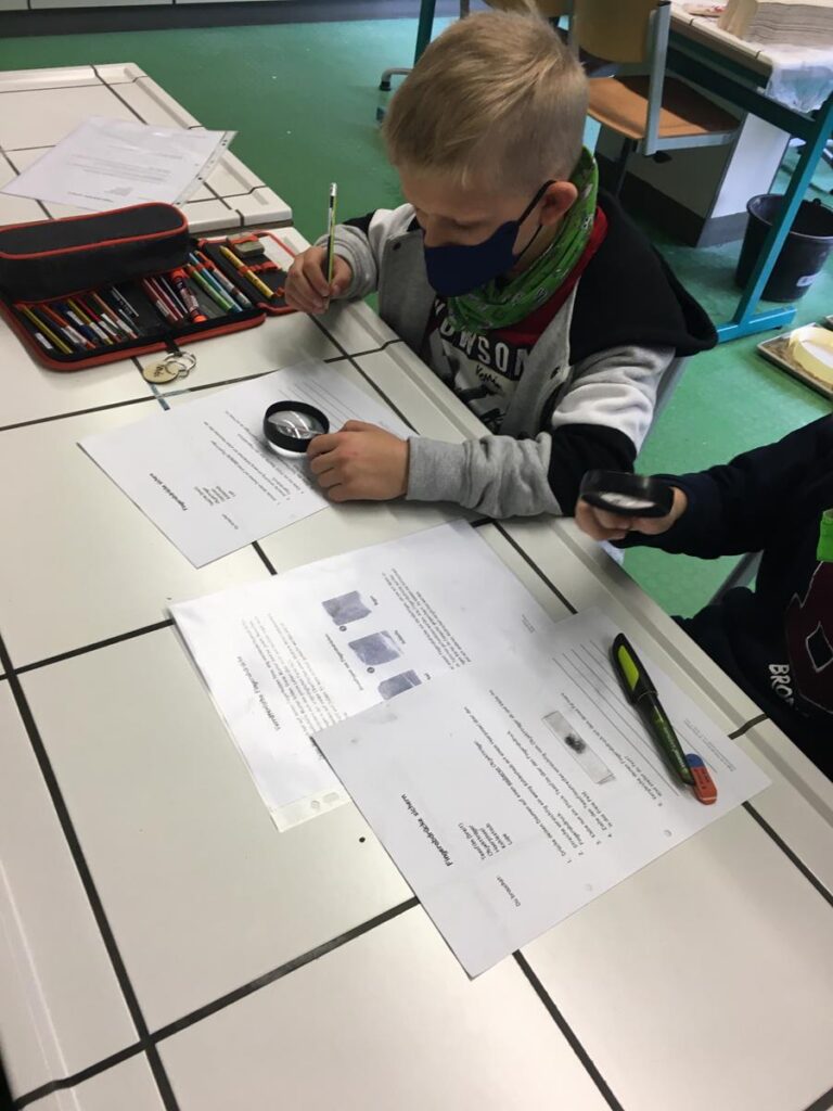 Ein Kind arbeitet an einem Tisch mit Unterlagen und Schreibmaterialien.