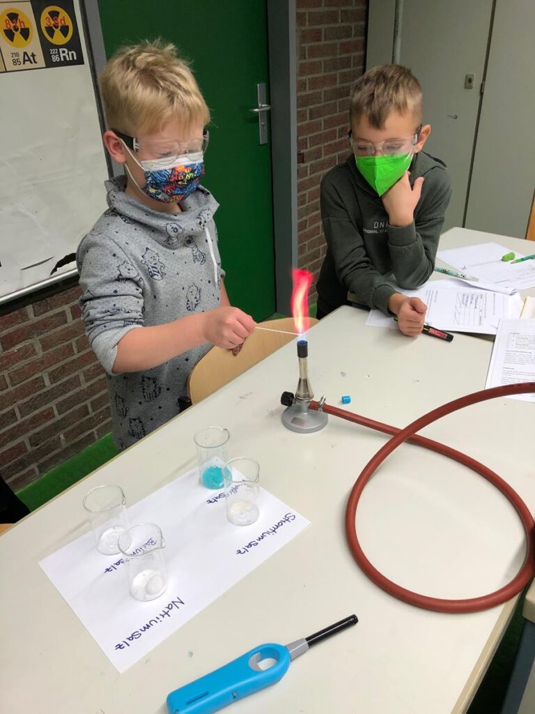 Ein Schüler experimentiert mit Feuer, während ein anderer zuschaut.