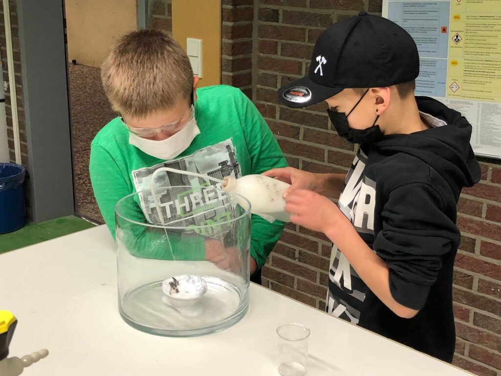 Zwei Schüler arbeiten gemeinsam an einem Experiment mit einem Behälter.