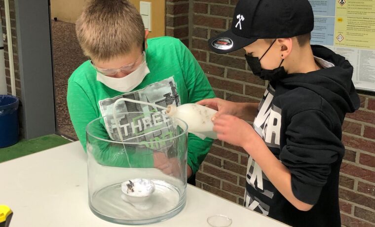 Zwei Schüler arbeiten gemeinsam an einem Experiment mit einem Behälter.
