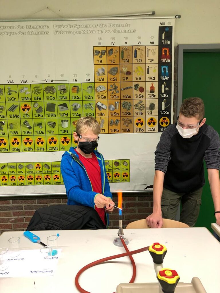Schüler führen ein Experiment mit einer Bunsenbrennerflamme durch.