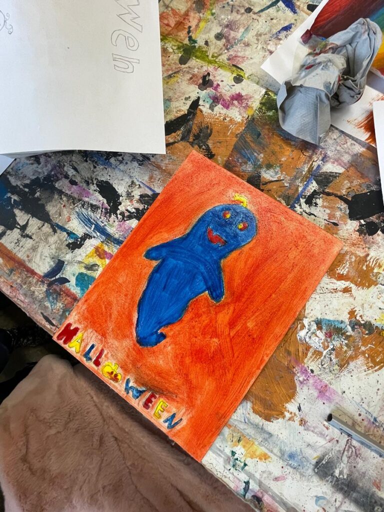 Kindliche Zeichnung eines blauen Gespensts auf orangefarbenem Hintergrund.