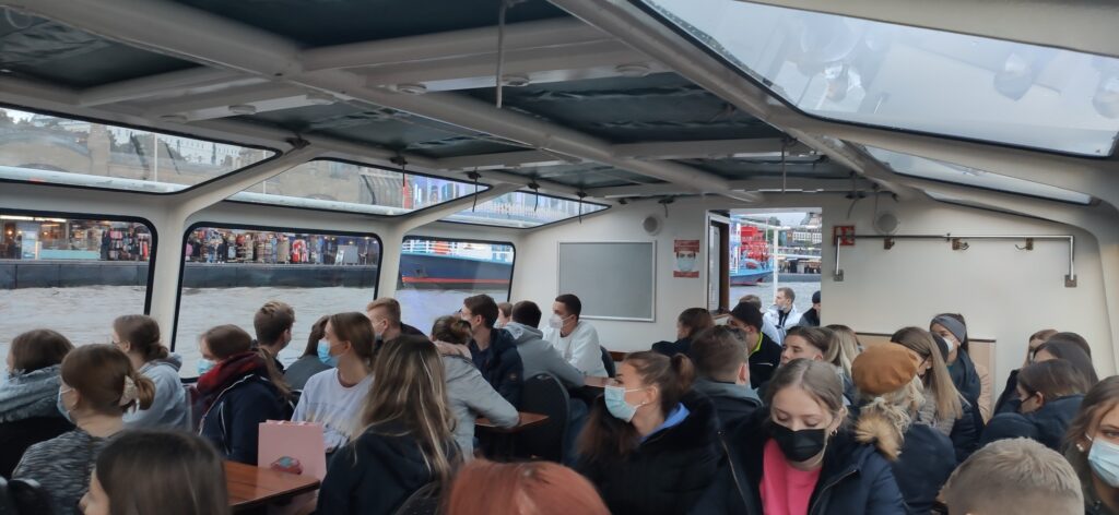 Schüler sitzen in einem Ausflugsboot und schauen nach draußen.