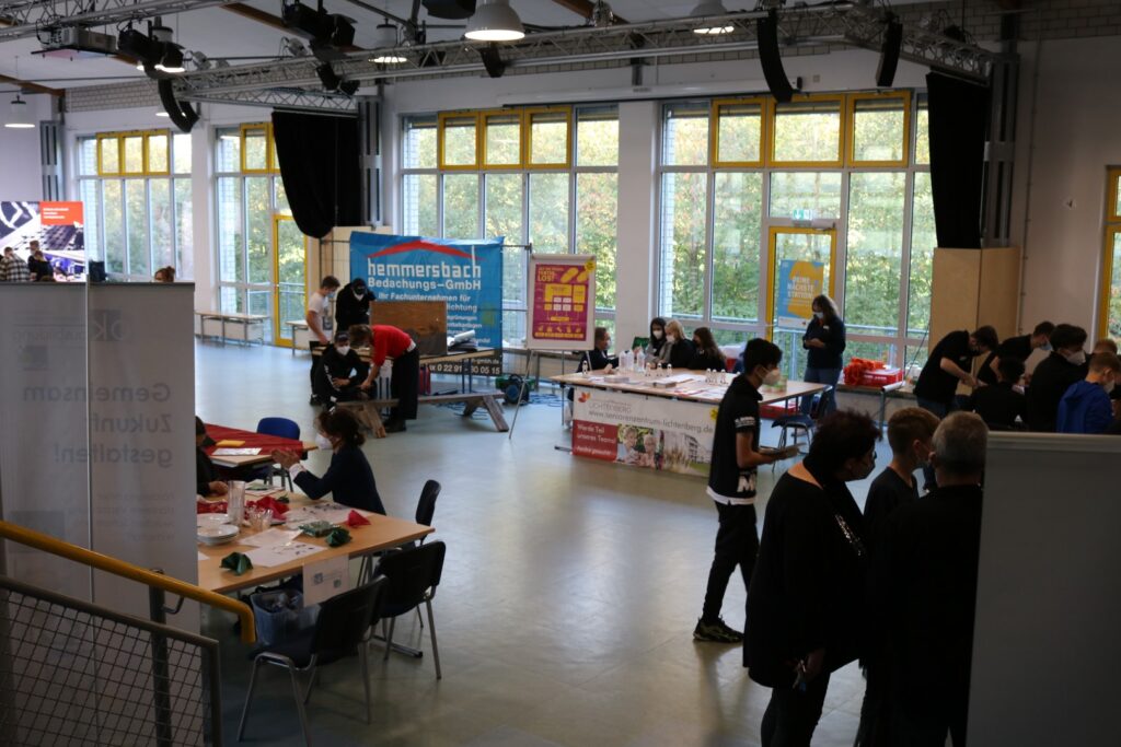Messe mit Ständen und Besuchern in einem großen Raum.