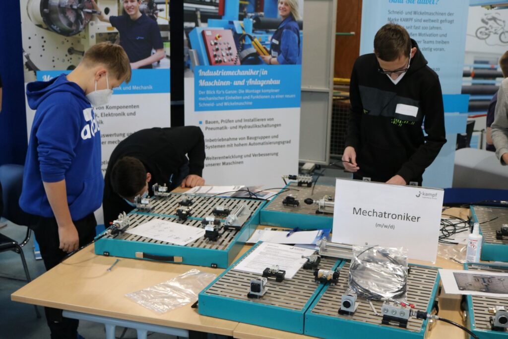 Schüler arbeiten an technischen Geräten an einem Tisch.