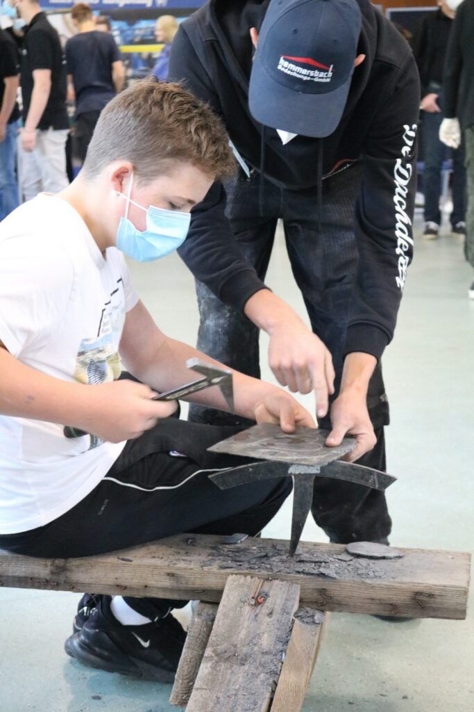 Zwei Personen arbeiten gemeinsam an einem Handwerksprojekt in einer Werkstatt.