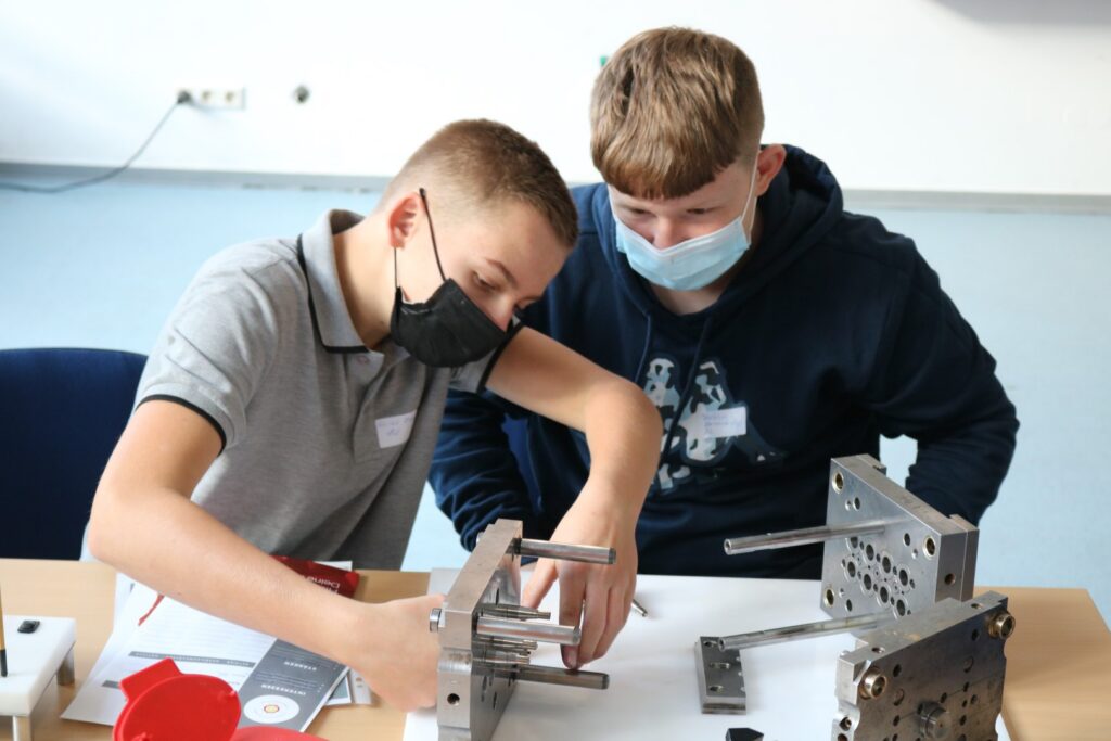 Zwei Schüler arbeiten an einem technischen Projekt und verwenden Werkzeuge.