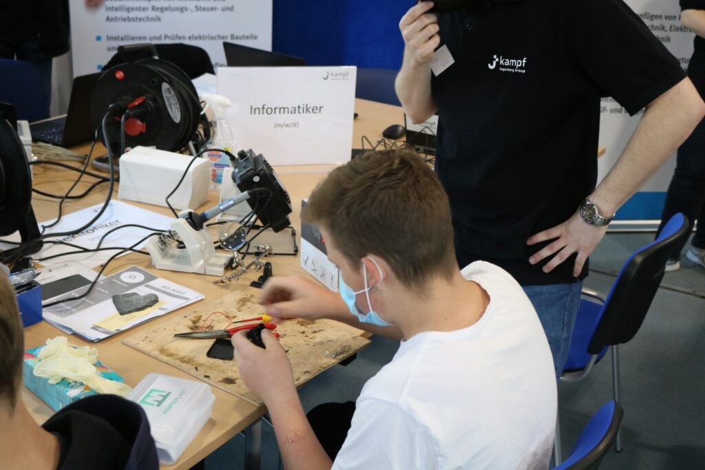Ein Schüler arbeitet an einem Tisch mit technischen Geräten und Werkzeugen.
