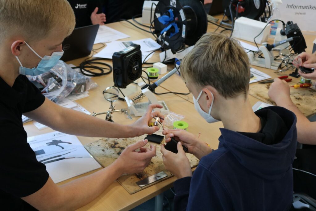 Schüler arbeiten gemeinsam an einem Technikprojekt am Tisch.