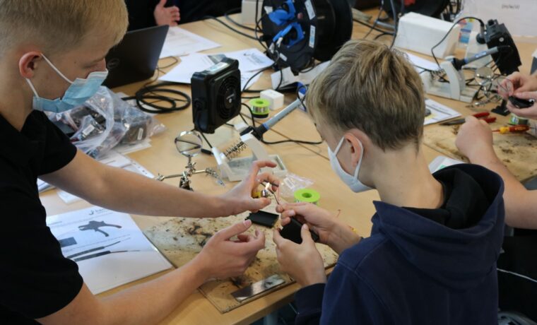 Schüler arbeiten gemeinsam an einem Technikprojekt am Tisch.