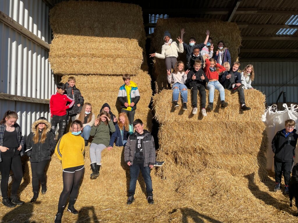 Gruppe von Schülern posiert auf Heuballen in einer Scheune.