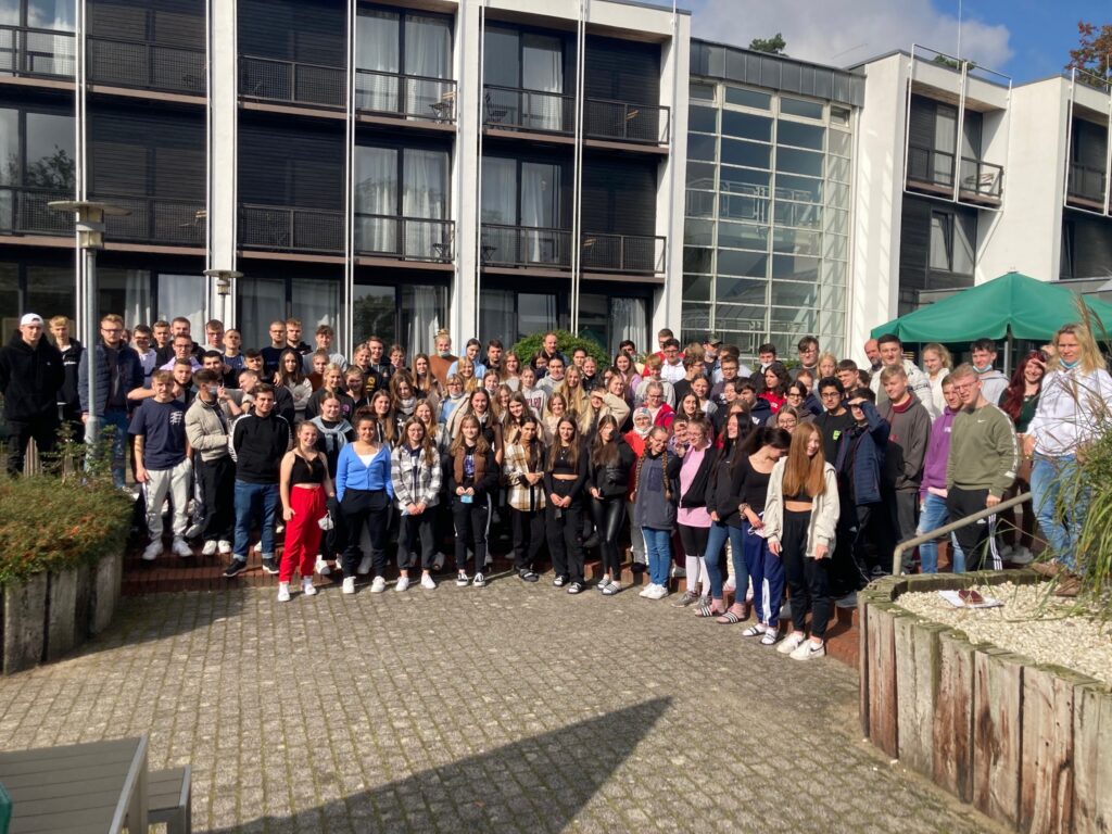 Gruppenfoto von Schülern und Lehrern vor einem modernen Gebäude im Freien.