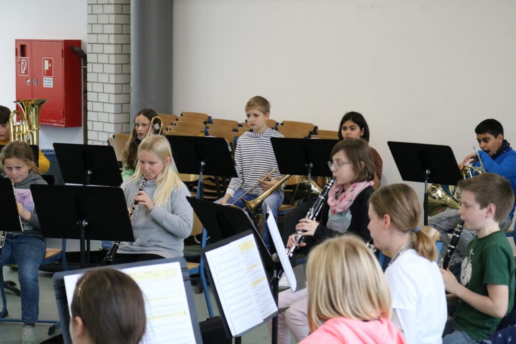 Schüler spielen gemeinsam in einem Musikensemble mit Notenständern.