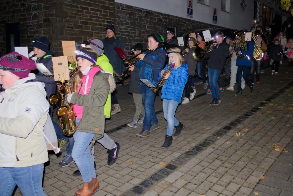 Musikgruppe marschiert auf einer Straße, Teilnehmer mit Instrumenten und warmen Kleidern.