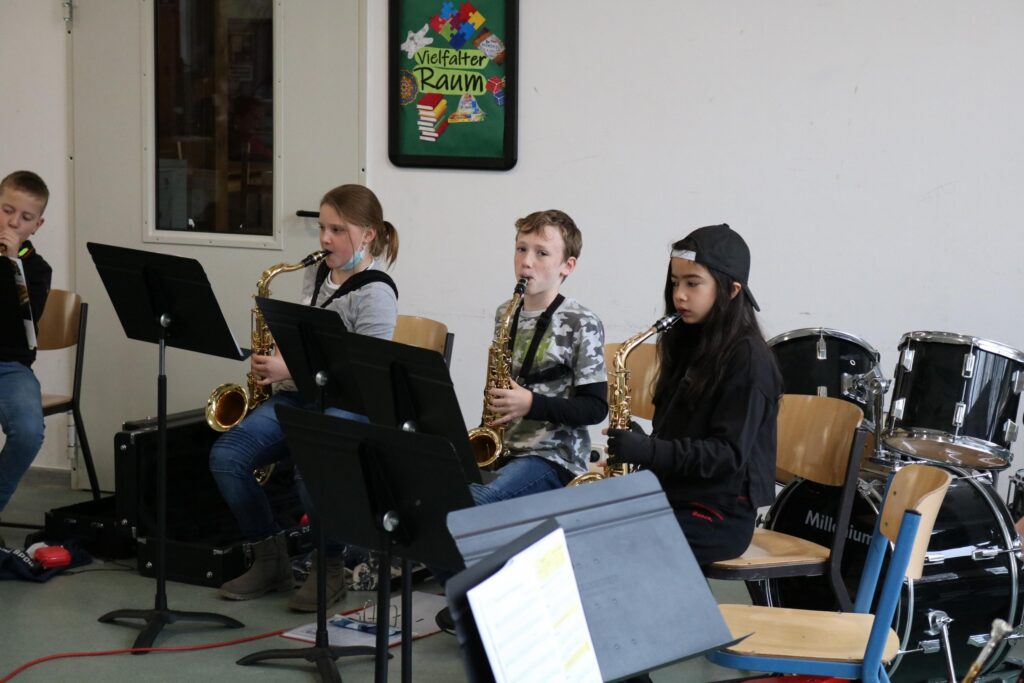Schüler spielen Saxophon in einem Musikraum. Schlagzeug im Hintergrund.