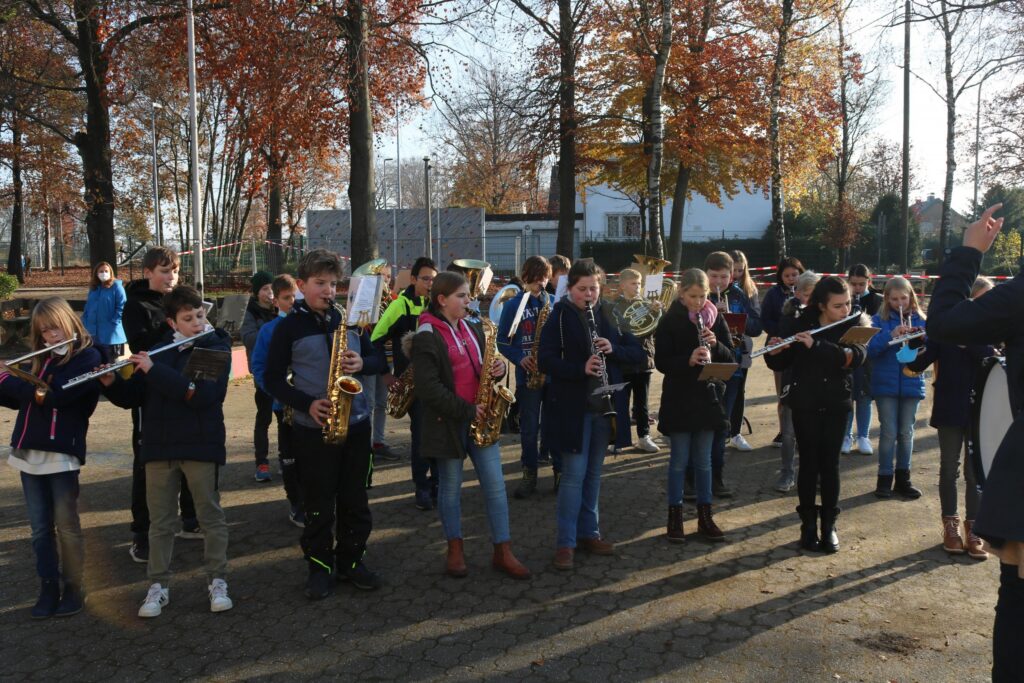 Schüler spielen in einer Gruppe Musikinstrumente im Freien.