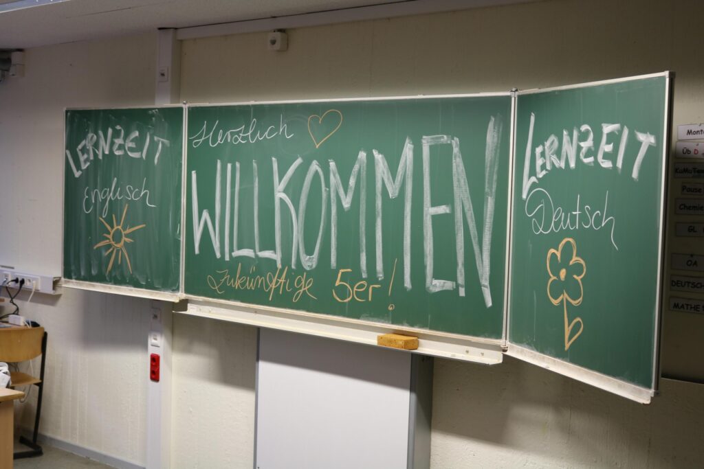 Zwei grüne Tafeln mit Begrüßungstext und Illustrationen.