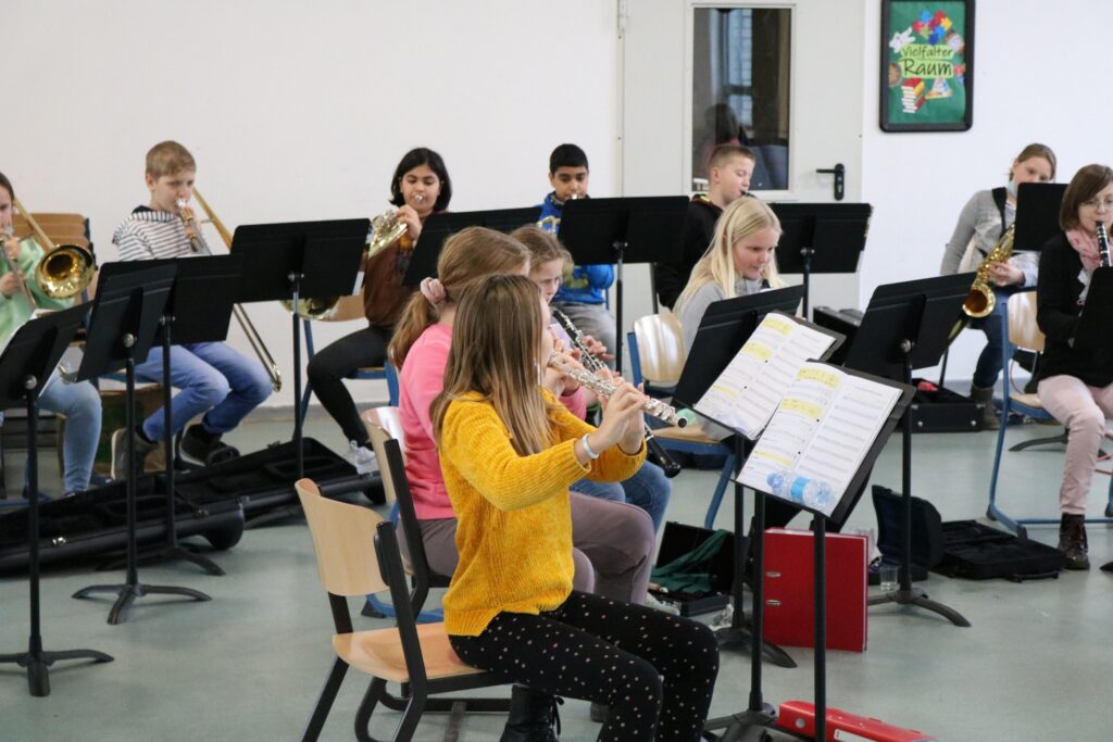 Schülerinnen und Schüler spielen in einem Musikraum gemeinsam Instrumente.