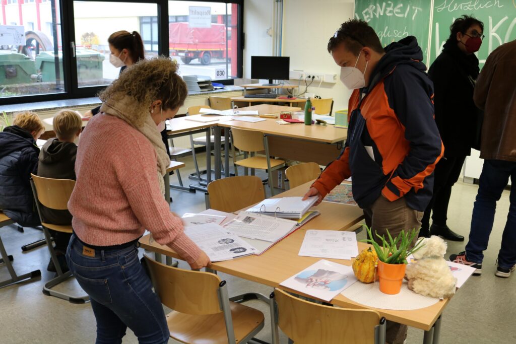 Lehrer und Schüler arbeiten an Tischen in einem Klassenraum.