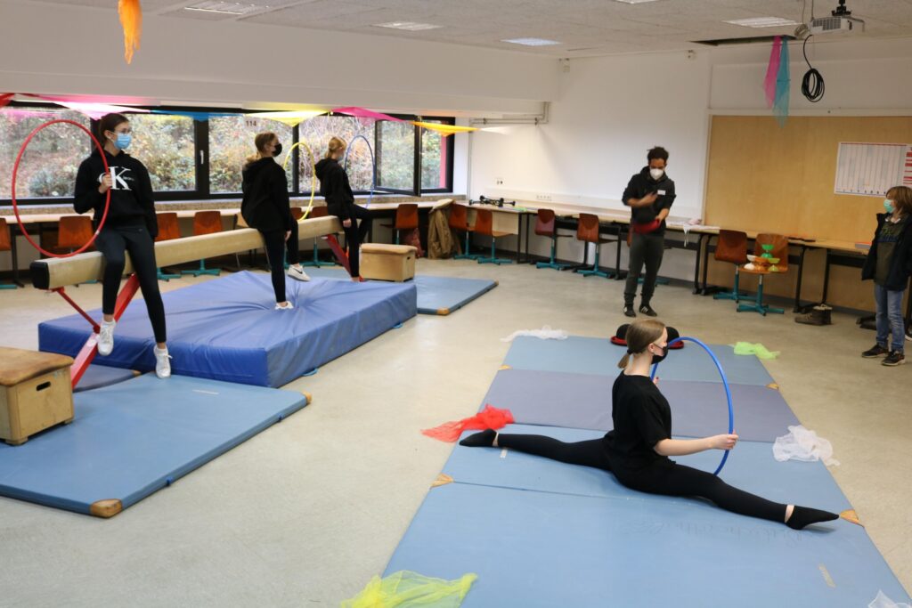 Schüler üben in einem Klassenraum mit Matten und Geräten.