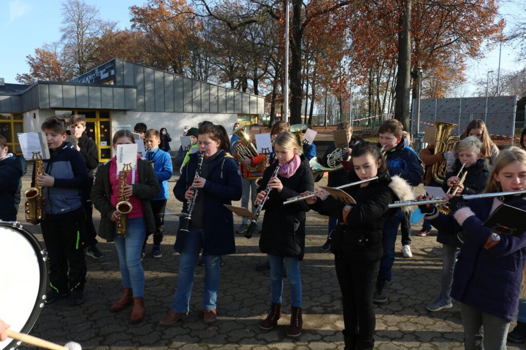 Schüler spielen in einer Gruppe Blasinstrumente im Freien.