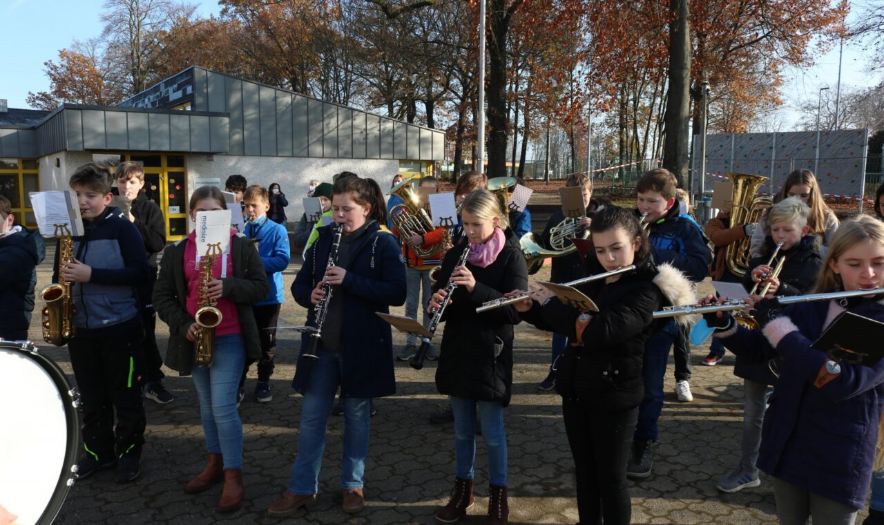 Schüler spielen in einer Gruppe Blasinstrumente im Freien.