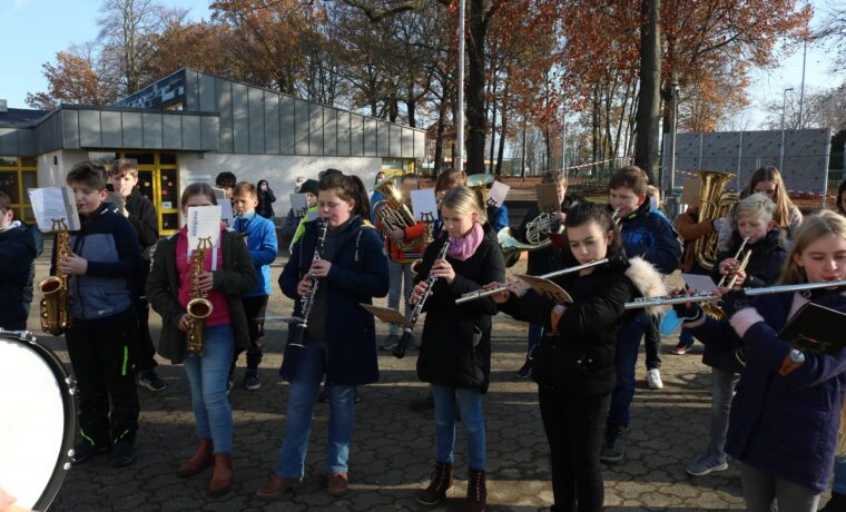 Schüler spielen in einer Gruppe Blasinstrumente im Freien.