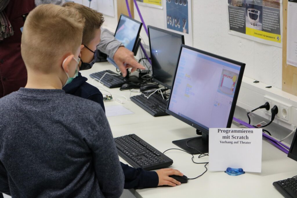 Kinder arbeiten an Computern mit Scratch-Programmiersoftware.